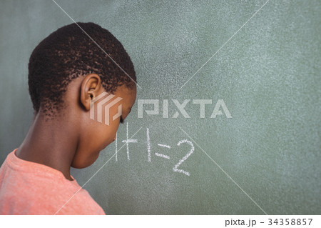 Boy standing by chalkboard Boy standing by chalkboard 34358857