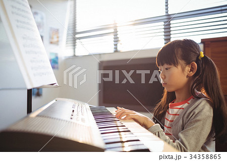 Concentrated girl practicing piano in class Concentrated girl practicing piano in class 34358865