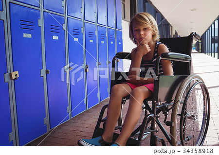 Portrait of schoolboy sitting on wheelchair in corridor Portrait of schoolboy sitting on wheelchair in corridor 34358918