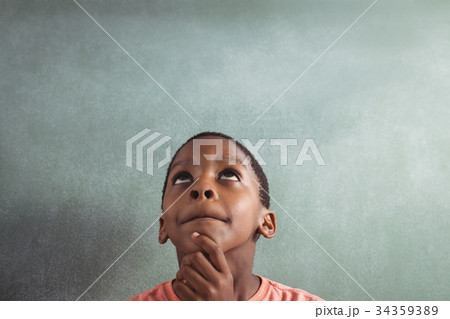 Thoughtful boy against greenboard in classroom 34359389