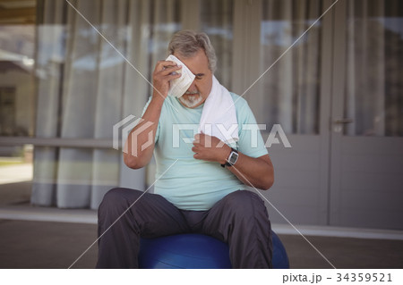 Senior man wiping sweat off his face with towel Senior man wiping sweat off his face with towel 34359521