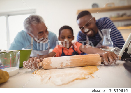 Boy preparing cookie dough with his father and grandfather in kitchen 34359616