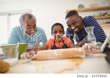 Boy preparing cookie dough with his father and grandfather in kitchen 34359662