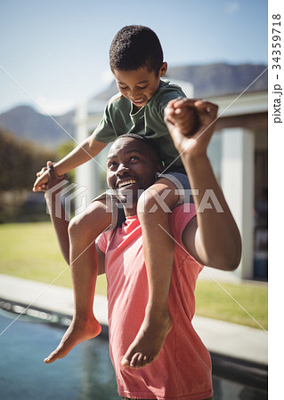 Father carrying son on shoulders near poolside 34359718