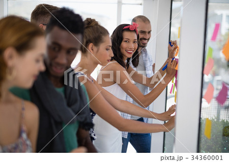 Team of executives writing on sticky notes Team of executives writing on sticky notes 34360001