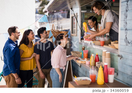 Smiling waiter giving order to customers at counter Smiling waiter giving order to customers at counter 34360059