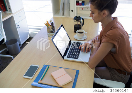 Female executive working over laptop at her desk 34360144