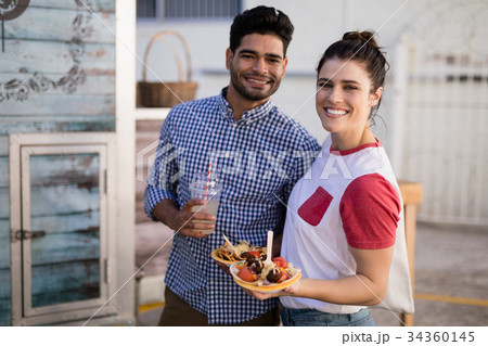 Smiling couple standing with snacks and juice 34360145