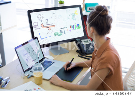Female executive working over graphic tablet at her desk Female executive working over graphic tablet at her desk 34360347