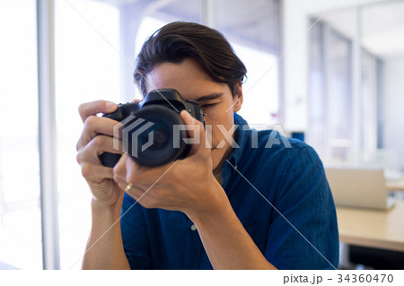 Male executive clicking a picture on digital camera Male executive clicking a picture on digital camera 34360470