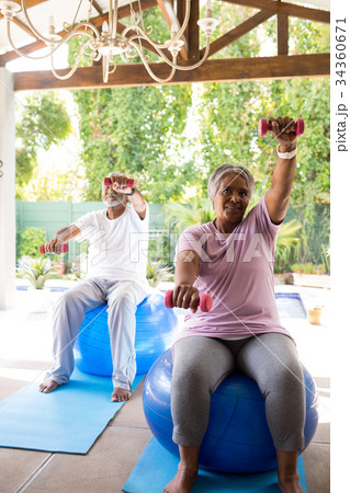 Full length of senior couple exercising with dumbbells Full length of senior couple exercising with dumbbells 34360671