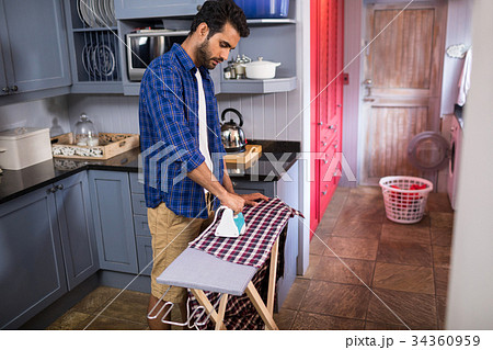 Side view of young man ironing shirt 34360959