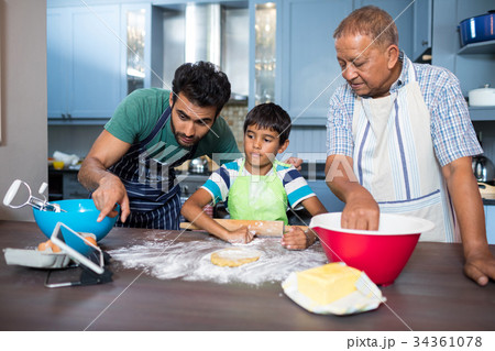 Man showing tablet to son while preparing food 34361078