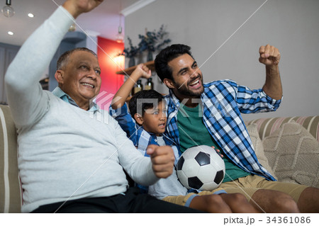 Happy family with arms raised watching soccer match 34361086