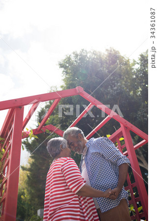 Low angle view of affectionate senior couple against sky Low angle view of affectionate senior couple against sky 34361087
