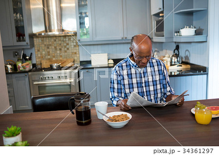 Senior man reading newspaper while having breakfast 34361297