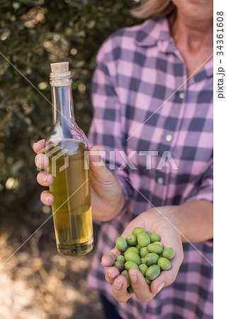 Woman holding olive oil and harvested olives 34361608