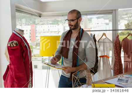 Designer writing on paper while looking at mannequin 34361646