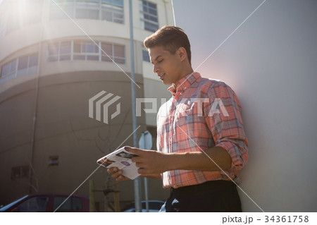 Man reading paper while standing by wall Man reading paper while standing by wall 34361758