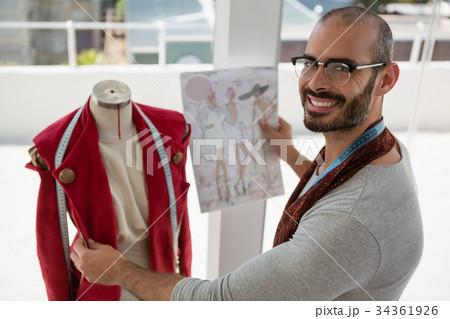 Portrait of smiling designer standing by mannequin 34361926