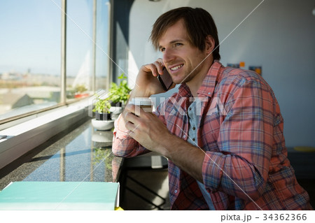 Businessman talking on phone while having coffee 34362366