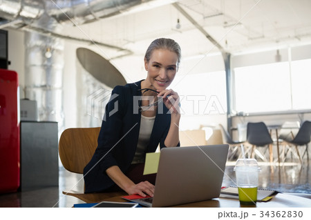 Portrait of smiling young woman using laptop in office 34362830