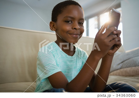 Boy using mobile phone in the living room at home Boy using mobile phone in the living room at home 34363060