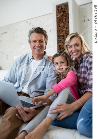Happy family using laptop together in living room Happy family using laptop together in living room 34363199