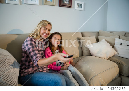 Mother and daughter watching television in the living room Mother and daughter watching television in the living room 34363222