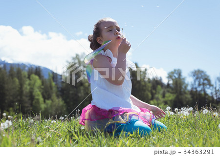 Girl blowing dandelion on grass Girl blowing dandelion on grass 34363291