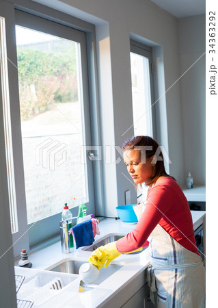 Woman washing utensil in kitchen sink 34363292