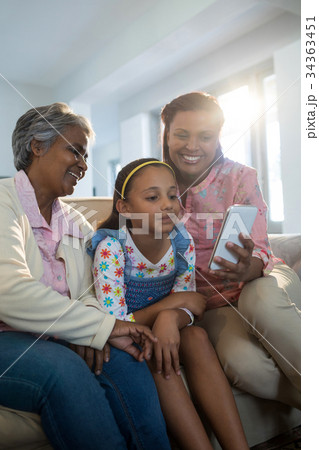Happy family using mobile phone in living room Happy family using mobile phone in living room 34363451