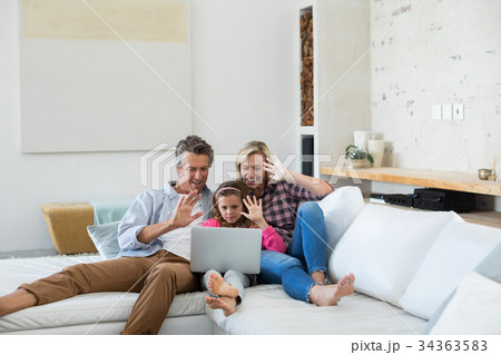 Family having a video call on laptop in living room 34363583