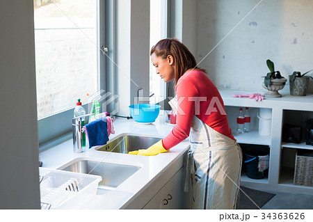 Woman washing utensil in kitchen sink 34363626