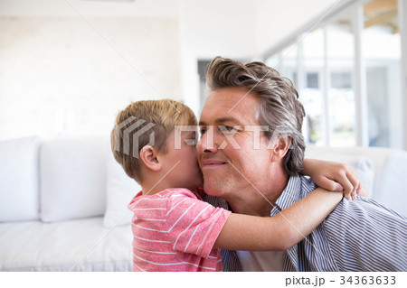 Son kissing father on his cheek in living room Son kissing father on his cheek in living room 34363633