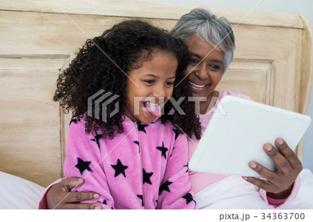 Grandmother and granddaughter using digital tablet in bed room Grandmother and granddaughter using digital tablet in bed room 34363700