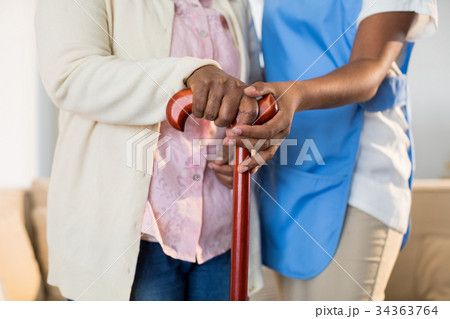 Female doctor helping senior woman to walk with walking stick 34363764