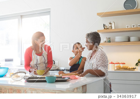 Girl feeding food to her grandmother in kitchen 34363917