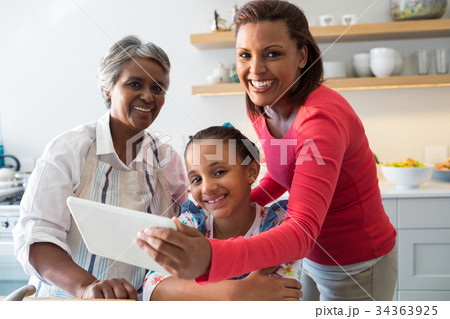 Multi-generation family using digital tablet in the kitchen Multi-generation family using digital tablet in the kitchen 34363925