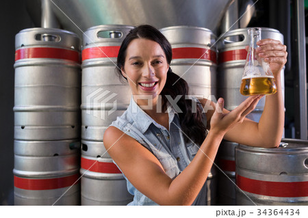 Portrait of smiling worker examining beer in beaker at factory Portrait of smiling worker examining beer in beaker at factory 34364434