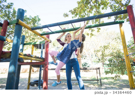Happy mother looking at daughter hanging on jungle gym 34364460