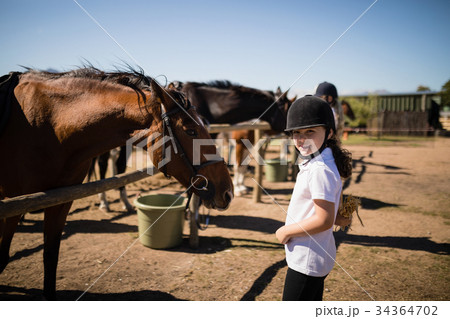 Smiling girl standing near the horse in ranch 34364702