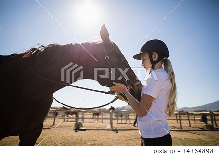 Rider girl caressing a horse in the ranch 34364898