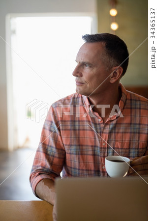 Man using laptop while having coffee Man using laptop while having coffee 34365137