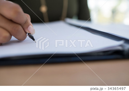 Female executive writing on a document at desk in the office 34365497