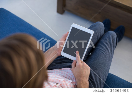 Male executive using digital tablet while sitting on sofa 34365498