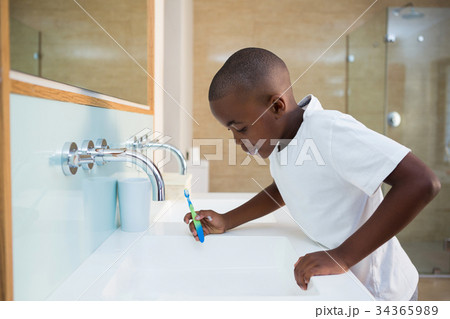 Side view of boy spitting in sink 34365989
