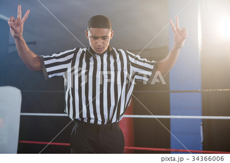 Young male referee gesturing while looking down in boxing ring Young male referee gesturing while looking down in boxing ring 34366006
