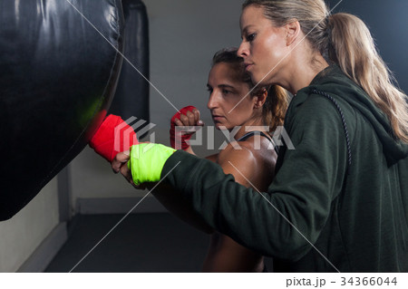 Trainer assisting woman in boxing Trainer assisting woman in boxing 34366044