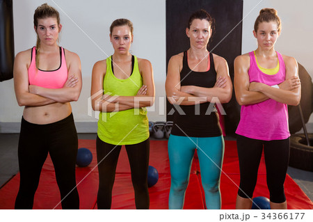 Portrait of female athletes standing with arms crossed on exercise mat 34366177